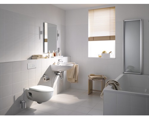 Salle de bains lumineuse avec toilettes, lavabo, miroir et baignoire