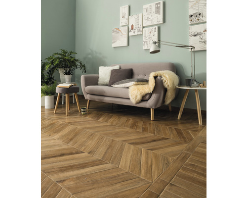 Salon avec canapé, lampe de table, plantes et plancher en bois à chevrons.