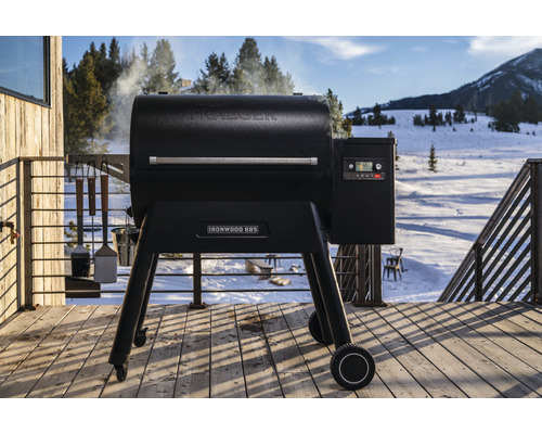 Traeger Ironwood 885 Pelletgrill auf einer Holzterrasse mit Winterlandschaft im Hintergrund