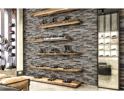 Schuhgeschäft mit Schuhen auf Holzregalen und Steinwand