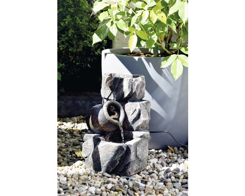 Fontaine de jardin décorative aspect pierre avec cruche à eau sur gravier