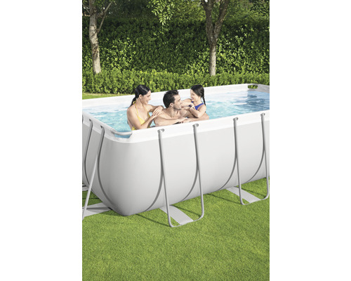 Famille se détendant dans une piscine hors-sol rectangulaire dans le jardin.
