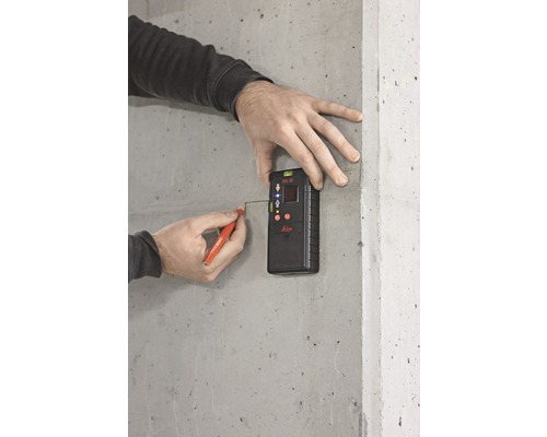 Eine Person benutzt einen Laser-Distanzmesser von Leica, um eine Messung an einer Betonwand durchzuführen und mit einem Stift eine Markierung zu setzen.