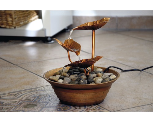 Fontaine d''intérieur décorative avec circulation d''eau sur des feuilles et des pierres
