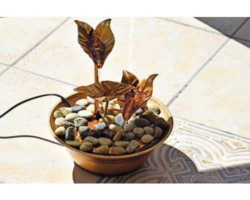 Fontaine d''intérieur avec des pierres et des feuilles couleur cuivre dans un bol