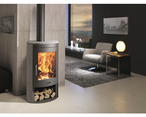 Wohnzimmer mit Kaminofen, Sessel und Fenster