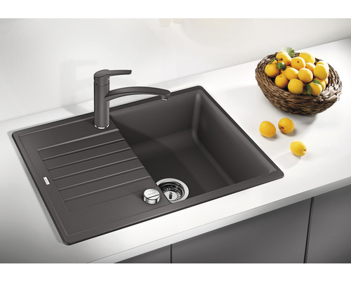 Évier de cuisine gris foncé avec égouttoir et robinet sur un plan de travail.