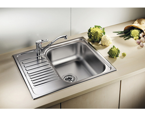 Évier en acier inoxydable avec égouttoir et robinet sur un comptoir de cuisine.