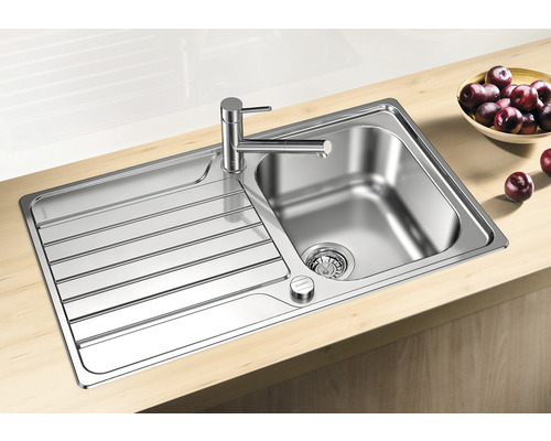 Edelstahlspüle mit Abtropffläche und Armatur auf einer Arbeitsplatte.