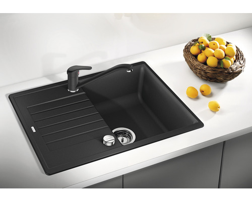 Schwarze Küchenspüle mit Abtropffläche und Armatur auf einer Küchentheke.