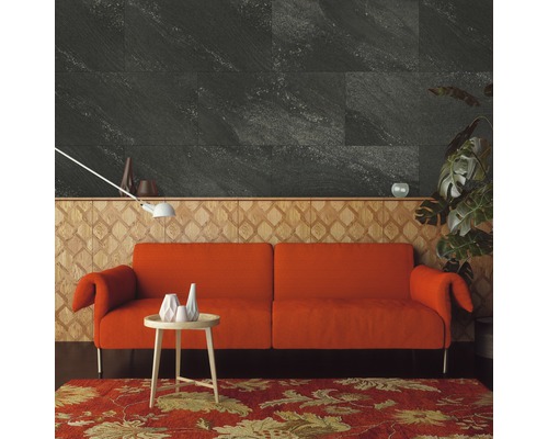 Salon avec carrelage mural gris aspect pierre, un canapé orange et un tapis à motifs