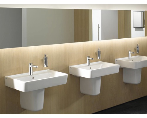 Trois lavabos blancs avec robinets et distributeurs de savon dans une salle de bain.