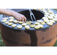 Person kocht Kartoffelscheiben auf einer Feuerstelle