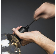 Eine Person befestigt eine Lampe an einer Aufhängung.