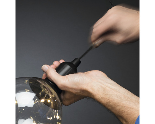 Eine Person befestigt eine Lampe an einer Aufhängung.