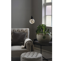 Wohnzimmer mit Sessel, Fusshocker, Tischleuchte und Zimmerpflanze