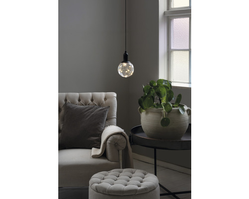 Wohnzimmer mit Sessel, Fusshocker, Tischleuchte und Zimmerpflanze