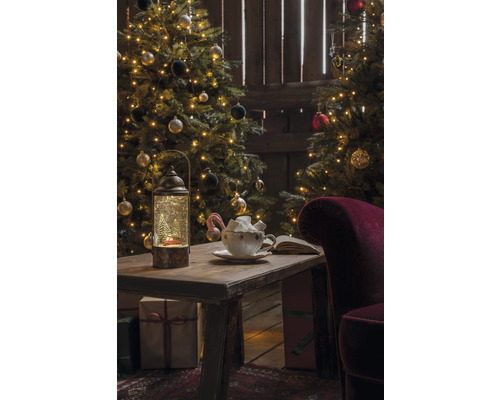 Scène de Noël avec sapins décorés, table avec lanterne, tasse et cadeaux