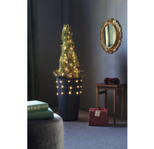 Arbre de Noël miniature décoré dans un pot avec des cadeaux dans une pièce