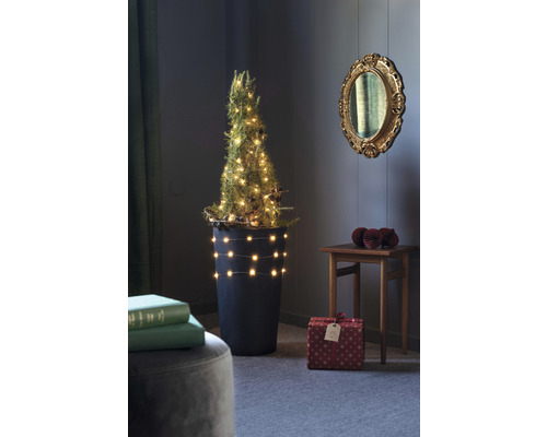 Arbre de Noël miniature décoré dans un pot avec des cadeaux dans une pièce