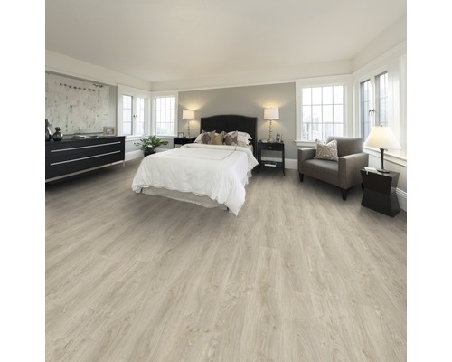 Heller, grosszügiger Schlafraum mit Laminatboden, Bett, Kommode und Sessel.