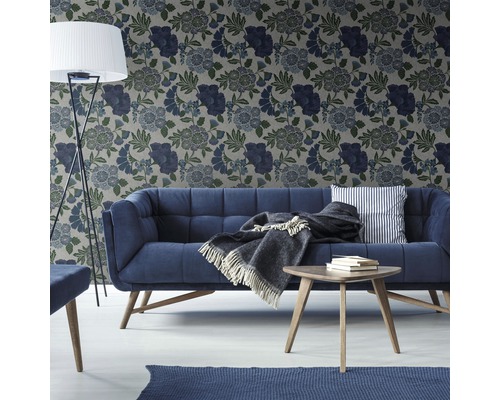 Wohnzimmer mit Sofa, Tisch, Stehlampe und floral gemusterter Tapete