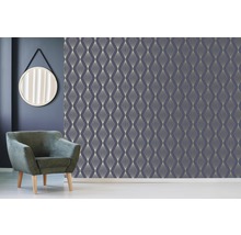 Szene mit einer Wand mit geometrischer Tapete, einem runden Spiegel und einem Sessel.