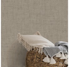 Dekokissen und Decke in einem Korb vor einer strukturierten Wand