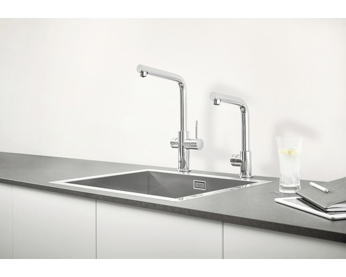 Évier de cuisine avec deux robinets et matériel de travail sur un plan de travail