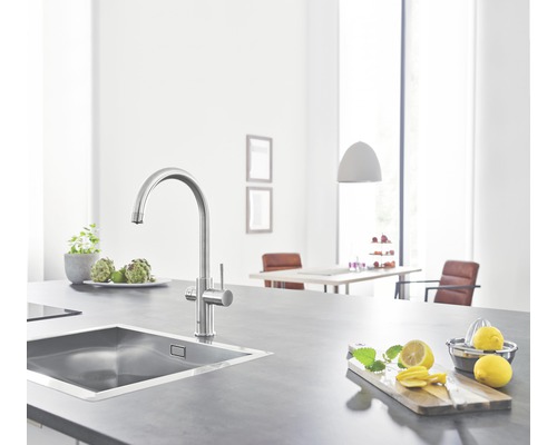 Évier de cuisine avec robinet sur un plan de travail avec des citrons et des herbes aromatiques.