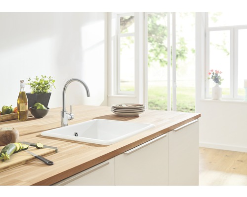 Cuisine lumineuse avec évier, robinet et plan de travail en bois.