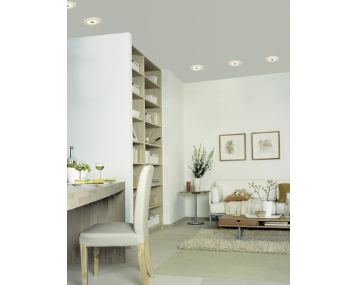 Salon avec spots encastrés, bibliothèque et coin salon.