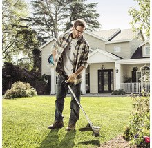Ein Mann benutzt einen Rasentrimmer im Garten.