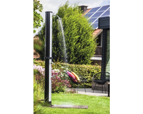 Gartenszene mit einer stehenden Außendusche auf einer Rasenfläche