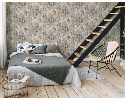 Ein Schlafzimmer mit einem Bett, einem Stuhl und einer Treppe vor einer Wandtapete mit Fleckmuster.