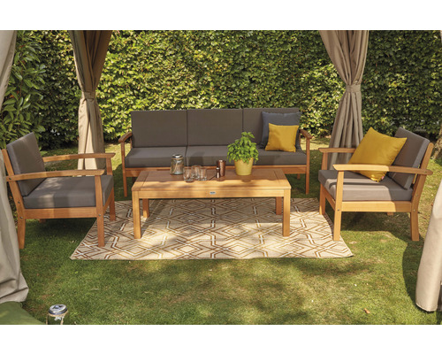 Gartenlounge-Set mit Sofa, Sesseln und Tisch auf einem geometrischen Teppich im Garten