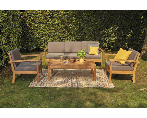 Gartensitzgruppe mit Sofa, zwei Sesseln und einem Tisch auf einem Teppich im Garten.