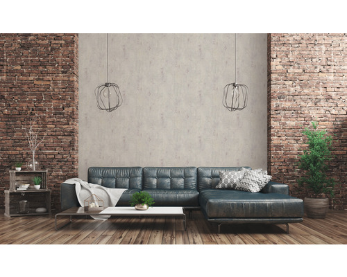 Wohnzimmer mit Ledersofa, Couchtisch, Regalen und dekorativen Elementen vor einer Backsteinwand