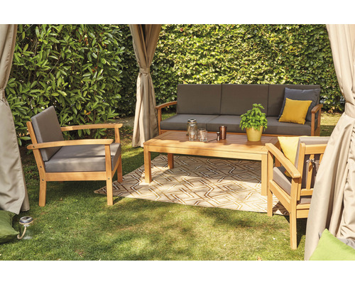 Gartensitzgruppe mit Sofa, Sessel und Tisch auf einem Teppich im Freien