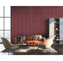 Salon avec un canapé en cuir marron, des fauteuils et un mur avec du papier peint géométrique