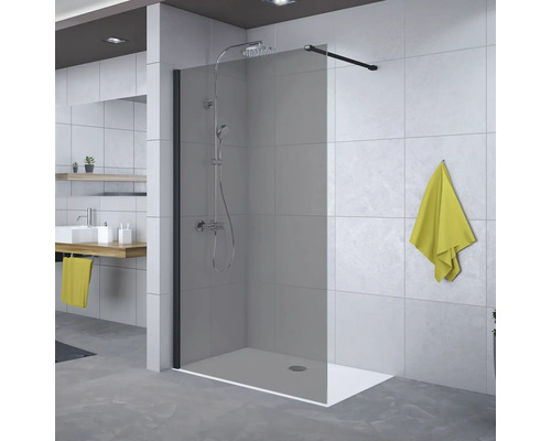 Begehbare Dusche mit getönter Glaswand, schwarzer Haltestange und integriertem Duschsystem in einem modern gefliesten Badezimmer.