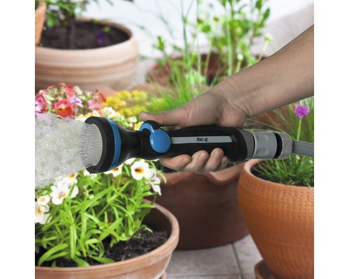 Eine Hand hält eine for.q Gartenspritze und bewässert Pflanzen.