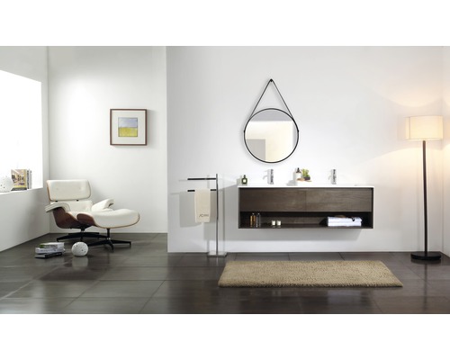 Salle de bains moderne avec meuble-lavabo double, miroir rond, fauteuil et lampadaire.