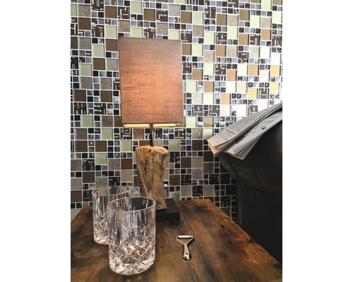 Table décorative avec lampe, deux verres et un ouvre-bouteille devant un mur en mosaïque