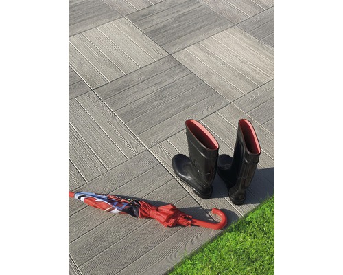 Dalles de terrasse aspect bois, bottes en caoutchouc et parapluie sur gazon