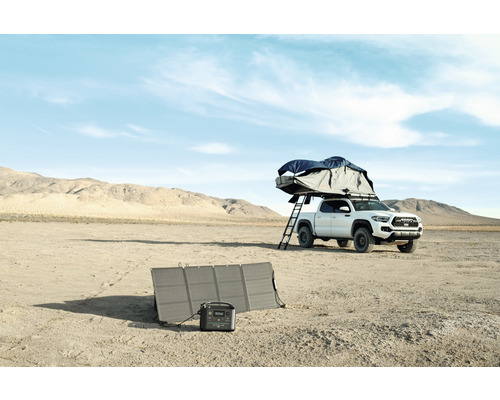 Équipement de camping avec panneau solaire et centrale électrique portable à côté d''un pick-up avec tente de toit dans le désert