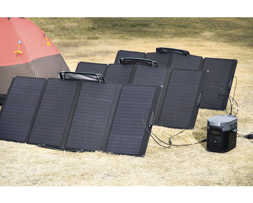 Plusieurs panneaux solaires au sol avec centrale électrique portable et tente en arrière-plan