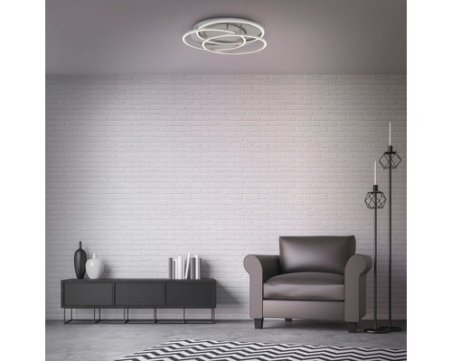 Salon avec plafonnier, fauteuil et décoration sur un buffet devant un mur de briques