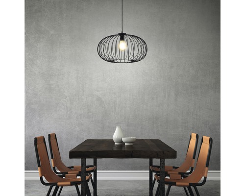 Salle à manger avec table en bois, chaises et suspension noire.