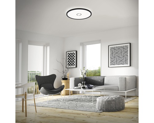 Wohnzimmer mit Deckenleuchte, Sofa, Sessel und Dekorationen